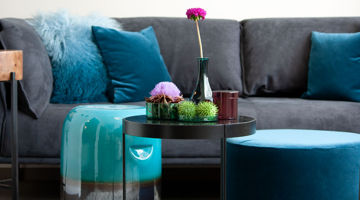 Farbberatung: Anthrazit Couch mit petrolfarbenen Kissen, Hocker und Beistelltisch