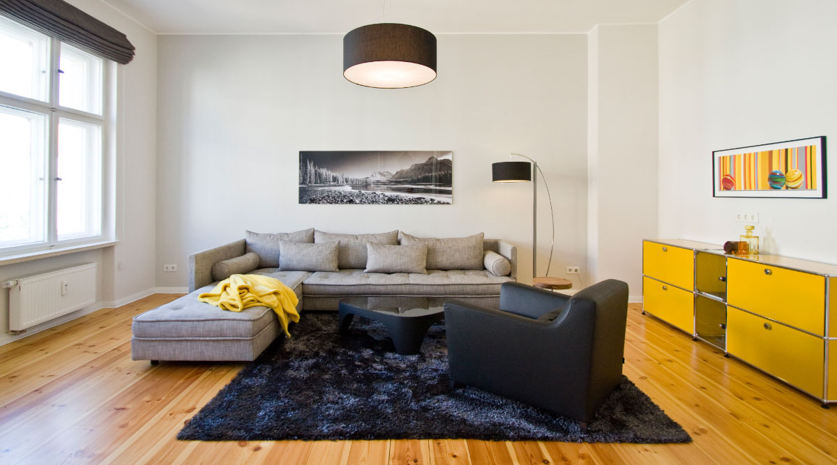 Wohnzimmer mit grauer Couch, schwarzem Sessel und gelbem Sideboard (Ligne Roset Lumas)