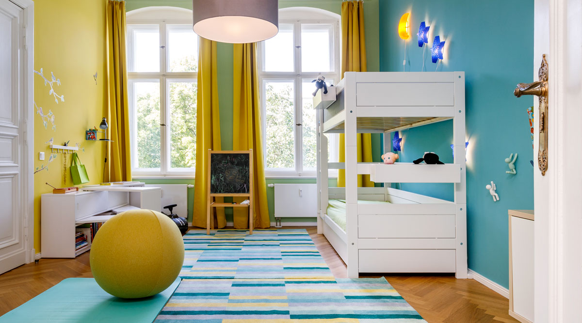 Schön renoviertes Kinderzimmer in gelb und hellblau mit weißer Möblierung und passendem Teppich